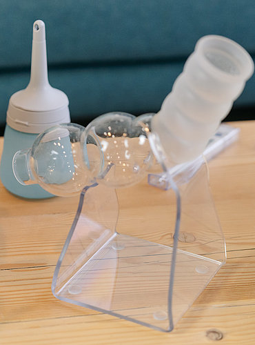 Transanales Irrigationsgerät mit transparentem Darmkatheter und Wasserreservoir, auf einem Tisch platziert.